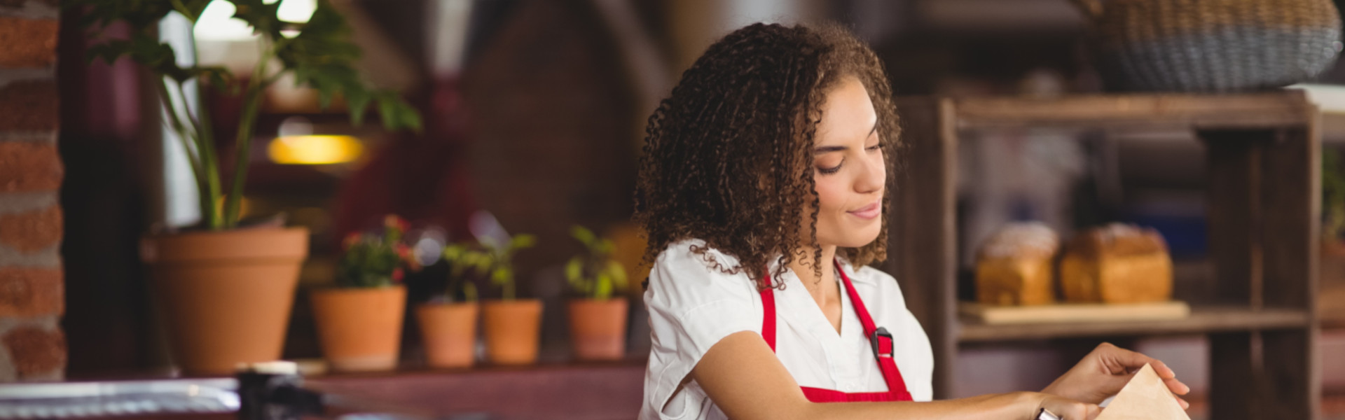 Verkäuferin packt frische Baguettes an der Bäckertheke ein.