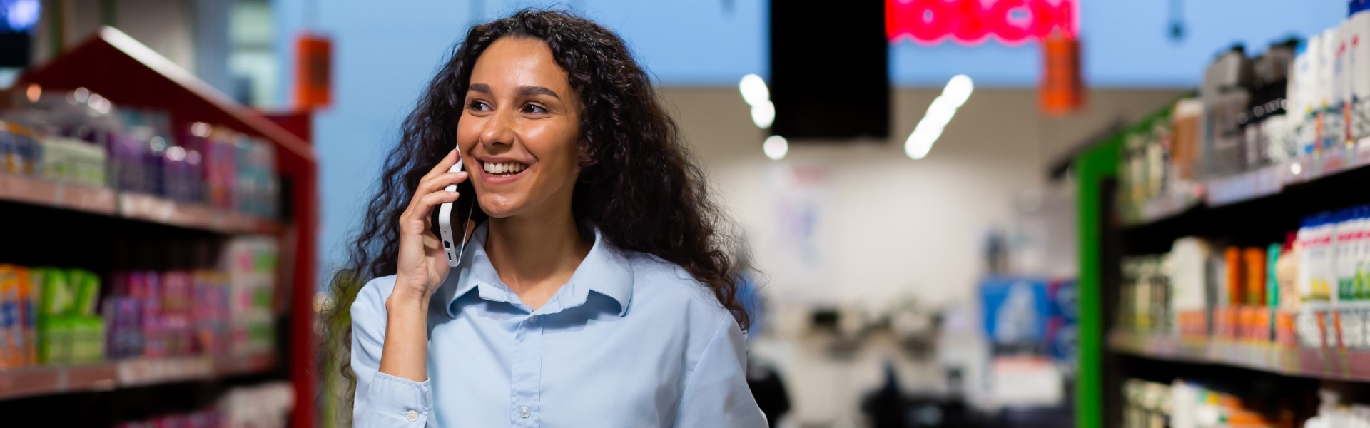 Frau mit Einkaufskorb telefoniert im Supermarktgang