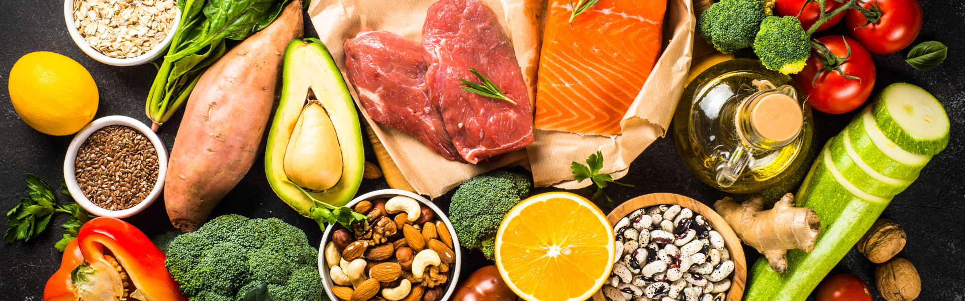 Bunte Auswahl frischer Lebensmittel: Gemüse, Obst, Nüsse, Eier, Fleisch und Lachs